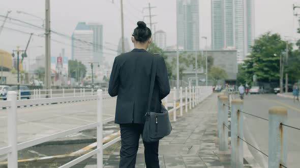 Asian businessman walking on the street in a city in the morning.