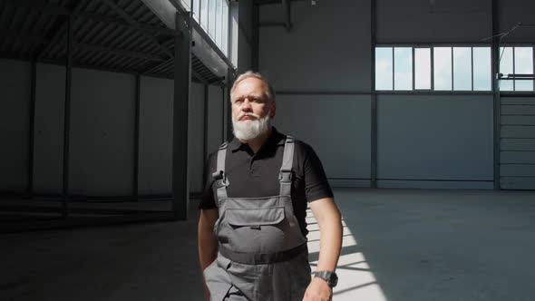 Slow Motion an Adult Grayhaired Man Worker Walks Through the Warehouse a Working Engineer Walks alt