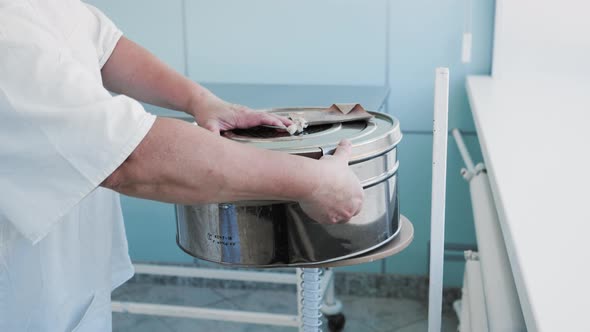 Female Surgical Nurse Worker Opens Steam Sterilizer Clean Drapes Inside alt