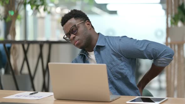 Young African Man Having Back Pain While Using Laptop alt