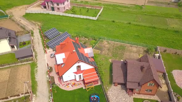 Aerial view of a house in residential area with solar panels on the roof. alt