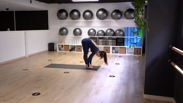 Woman doing Sun Salutation cycle of asanas in gym alt
