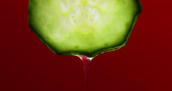 Gel, juice drips from cucumber slices with gel on red background