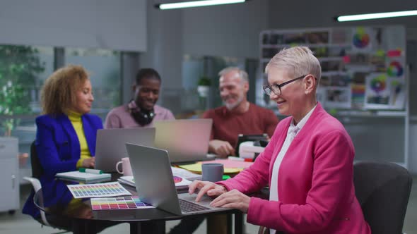 Happy Mature Editor Work on Magazine Issue with Team Brainstorm and Discuss on Background alt