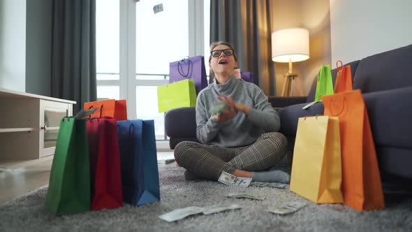 Happy Woman Is Sitting on a Carpet in a Cozy Room Among Shopping Bags and Making Money Rain From US alt
