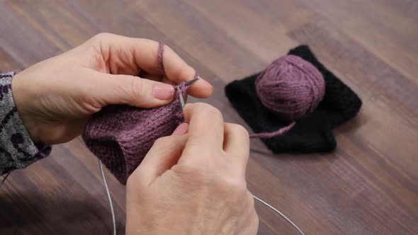 Woman Knits Mittens from Purple Yarn