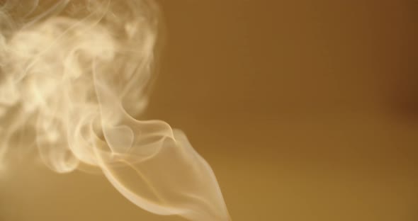 Close Up White Smoke Curling on Yellow Orange Background Slow Motion. Vapor Steaming From Incense alt