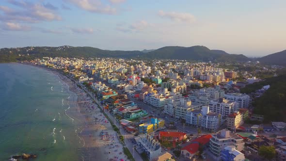 Aerial establishing shot of Bombas beach, a coastal city in Brazil at golden hour. Dolly in alt