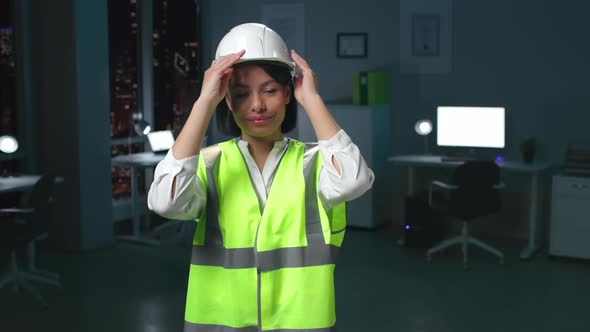 AfricanAmerican Woman Architect Put on Hardhat Looking at Camera Standing in Dark Office alt
