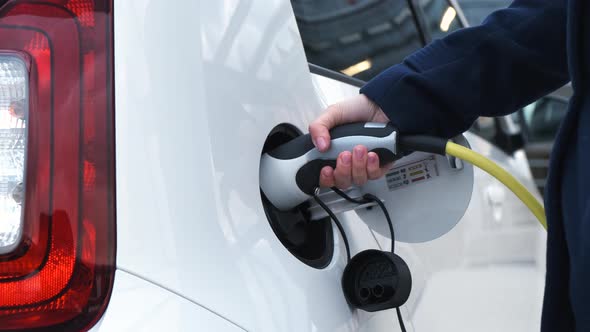 Close Up Woman Hand Takes Out Power Cable From Electric Car alt