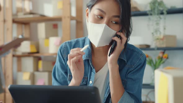 Asia businesswomen wear face mask using mobile phone call receiving purchase order and check product