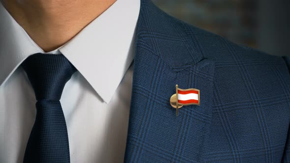 Businessman Walking Towards Camera With Country Flag Pin Austria alt