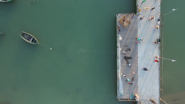 Fisherman Throws Out Fishing Net in the Sea from Pier, Aerial Top Down alt