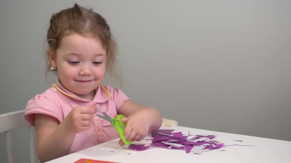 A Little Girl Cuts Scissors with Colored Application Paper. Outdoor Children 's Master Class