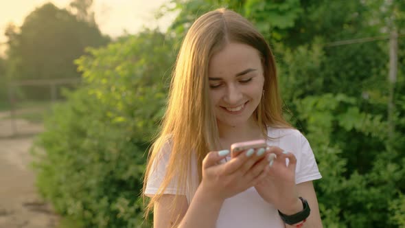 Portrait of a Beautiful Woman Typing on a Mobile Phone in the Park alt