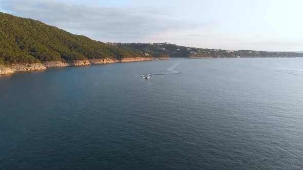 Head on shot of a boat pulling a wakeboard with the cliffs of lake travis in the background. Shot on alt