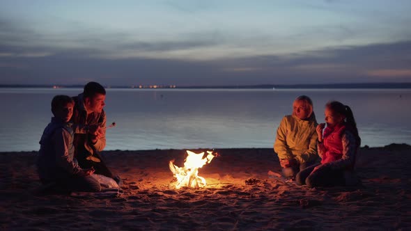 Family Dinner By Campfire on Beach at Night