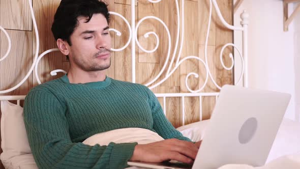 Man Sitting in Bed Working on Laptop alt