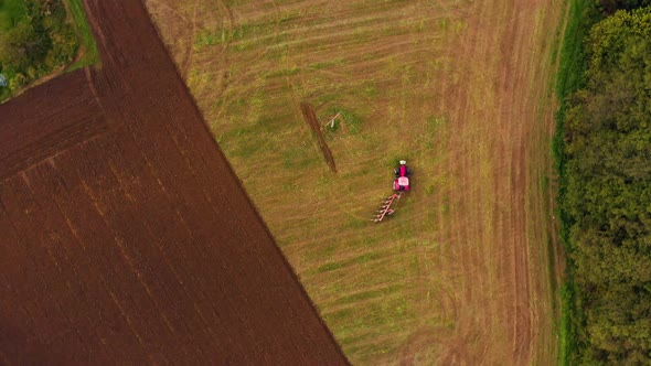 Farmer working od the ffarm field driving red tractor alt
