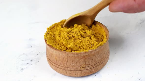 Chef Taking with Wooden Spoon Spices Ground Curry or Turmeric From Wooden Spice Jar alt