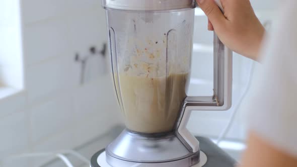 Making fruit smoothies, women's hands with a blender. Healthy diet at home in the kitchen alt
