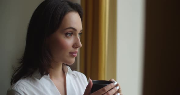 Elegant Woman Drinking Hot Tea Indoors Looking To Window Calm Expression
