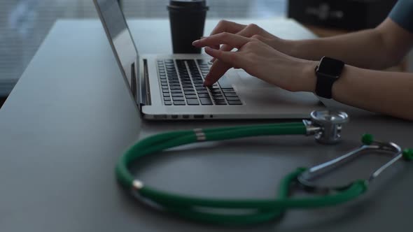 Tracking Shot Closeup of Hands of Unrecognizable Female Practitioner Doctor Using Typing on Laptop alt