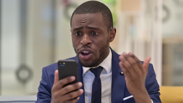 Portrait of African Businessman Having Loss on Smartphone  alt