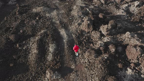 Anonymous Sportive Male Traveler Running Across Black Lava Rocks