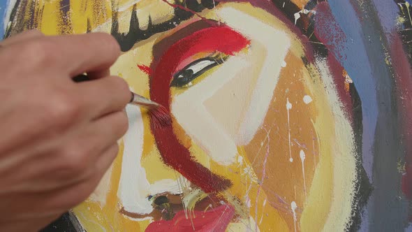 Close Up Of A Hand Holding Paintbrush Mixed Colour And Painting A Girl's Nose On The Canvas alt