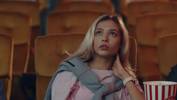 young caucasian woman watching horror movie in cinema theate. alt