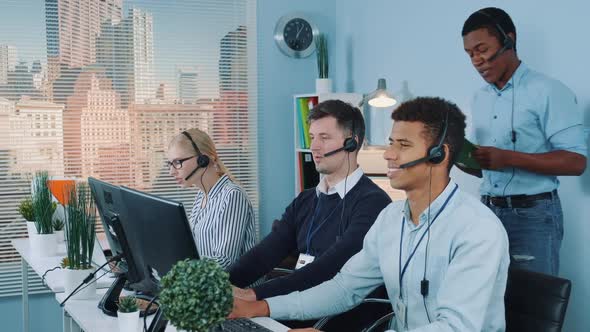 Multiethnic Customer Service Representative Telling His Colleagues a Joke While Calling To Clients alt