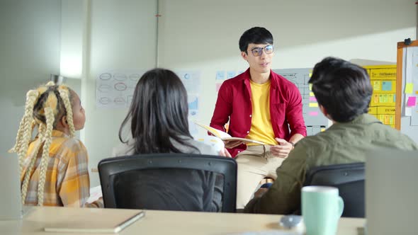 asian male designer present new business plan to his team in office