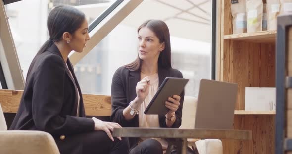 Two Women Sitting and Working in a Modern and Industrial Style Cafe alt