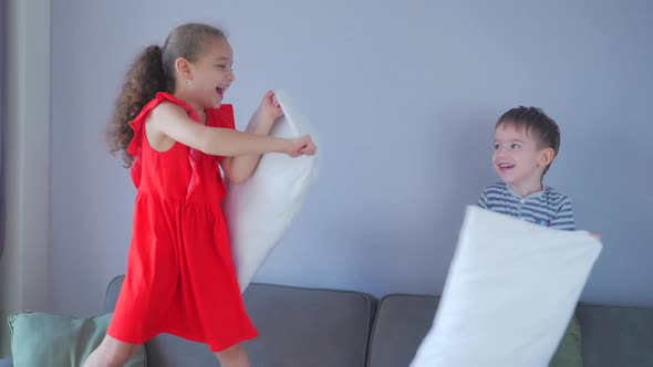 Happy Family Young Baby Sister and Little Kid Brother Enjoy Funny Pillow Fight on Bed, Brother and alt