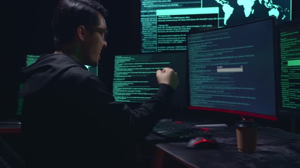 Asian Male Hacker Using Multiple Computer Hacking And Success Downloading Data alt