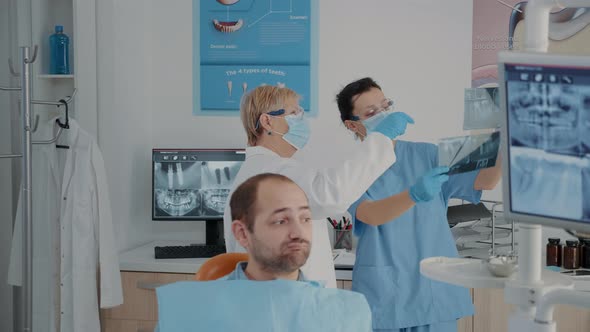 Senior Dentist and Nurse Analyzing x Ray Scan to Find Diagnosis alt