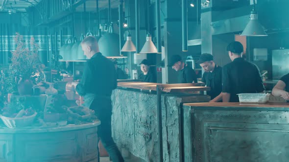 Open Kitchen of a Restaurant with Personnel in Uniforms alt