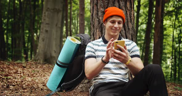 Man Relaxing in Forest Near Tree with Phone