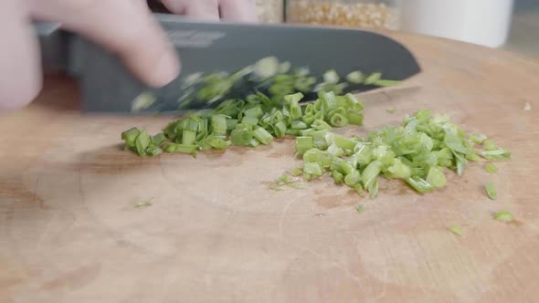 Slider Shot of Chopping Green Onions With a Chef's Knife on a Wooden Cutting Board alt