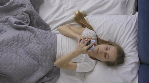 Joyful Girl Stretching in Bed and Taking Cellphone alt
