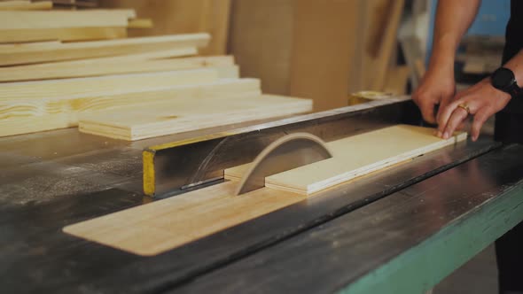 A Running Blade on a Bench Saw Sawing Trough the Wooden Log in the Middle of a Working Space Close alt