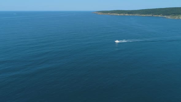 White Boat Quickly Floating on the Calm Water Surface and Leaving a Trail on the Sea alt