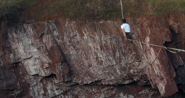 Amazing Man Is Standing Up on the Slackline Over a Huge Quarry alt