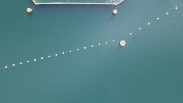 Emerald green water directly behind the Kokanee Lake Dam, aerial God view alt