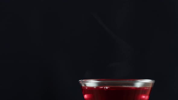 Red Fruit Tea in Glass Cup on Black Background alt
