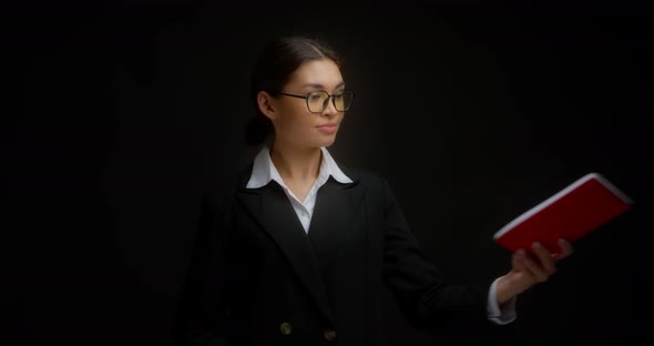Woman Boss with Glasses is Handed a Red Notebook