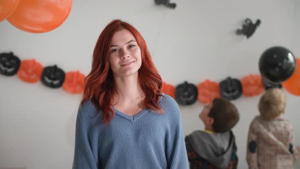 Portrait of Mom Happy Young Woman Looks at the Camera and Smiles on Background of Children Playing
