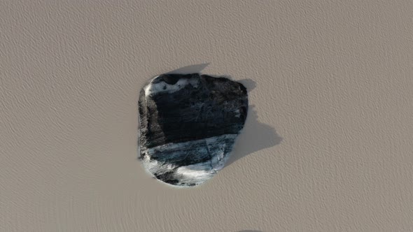 Top View Of Rocky Outcrop With Water Flowing At The Solheimajokull Glacier Lagoon In Iceland. alt