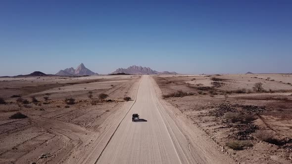 Car Driving on Gravel Road in Aerial Desert